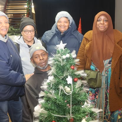 A family standing together beside the Christmas tree at the holiday gift event