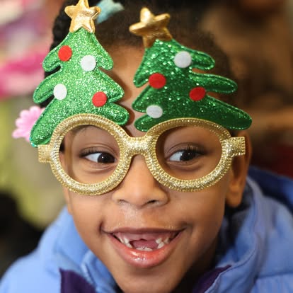 A child wearing novelty Christmas-tree glasses at the holiday party